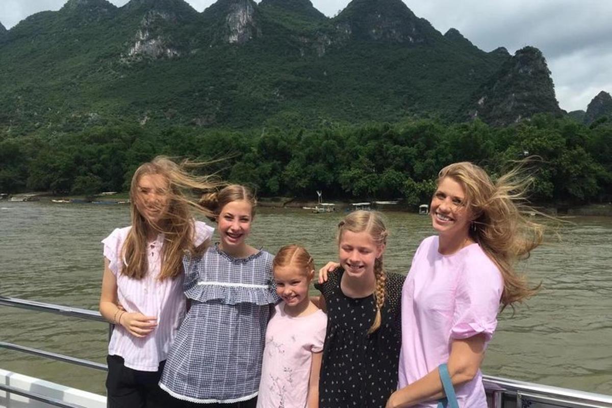 a group of girls standing on a boat on the water