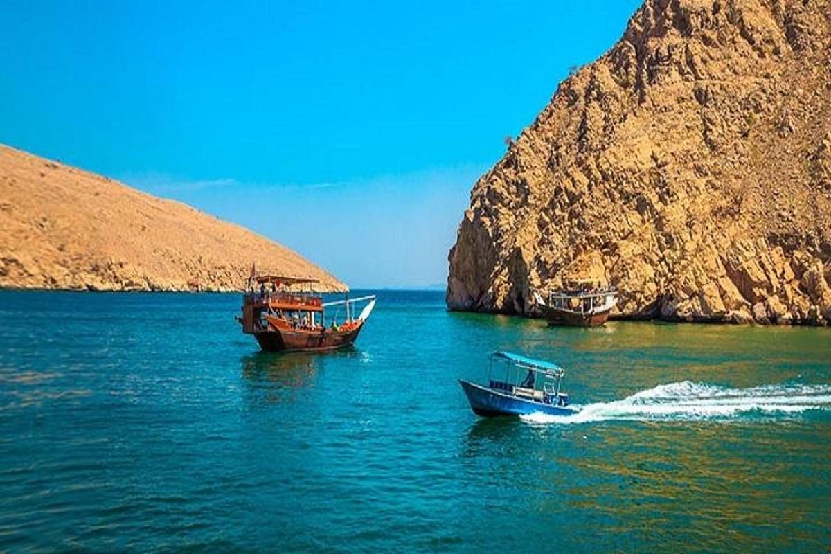 three boats in the water next to a mountain