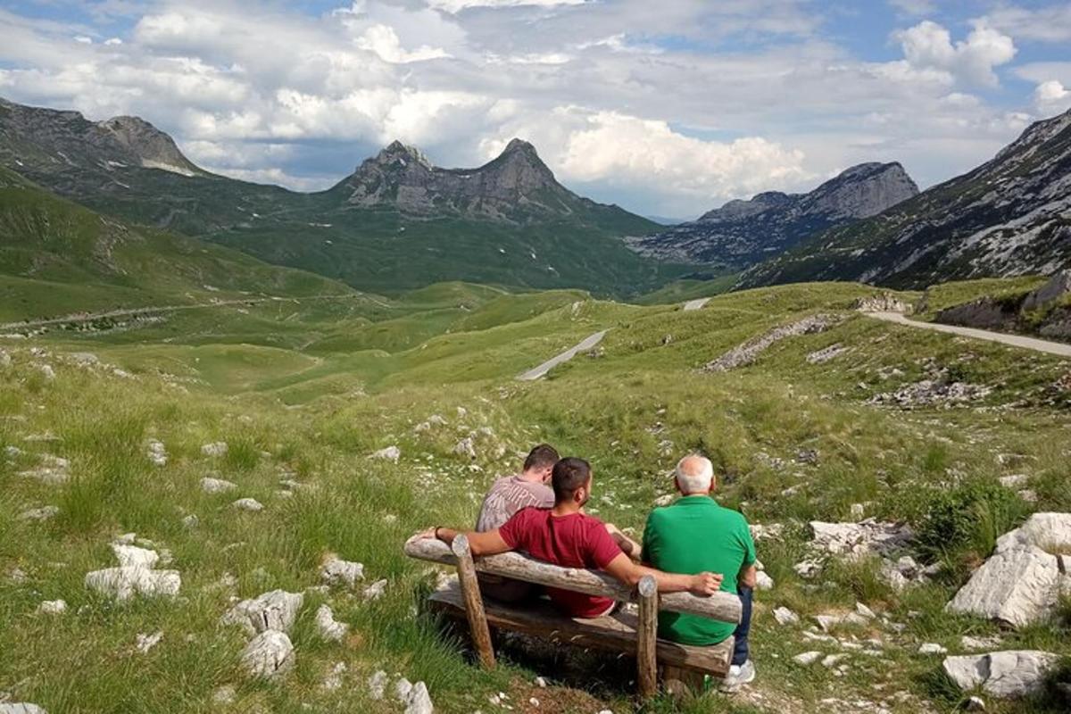 Þriggja manna hópur situr á bekk úti í túni