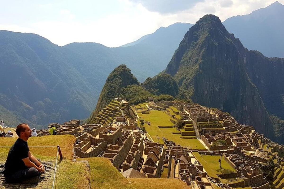 một người đàn ông ngồi trên mỏm đá nhìn ra quang cảnh của một ngọn núi