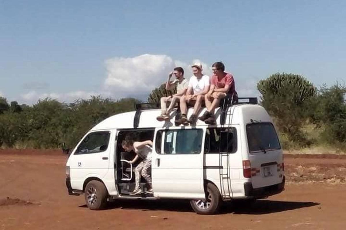skupina lidí sedících na střeše dodávky