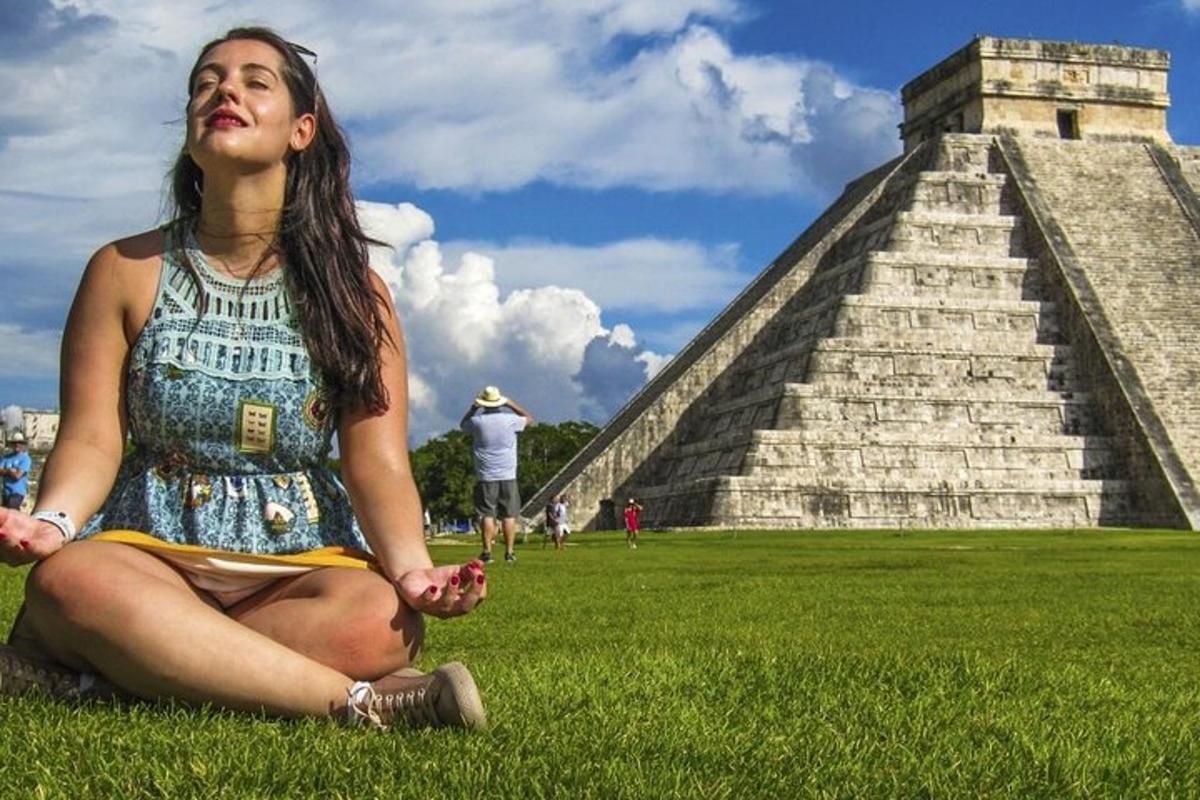 uma mulher sentada na grama em frente a uma pirâmide