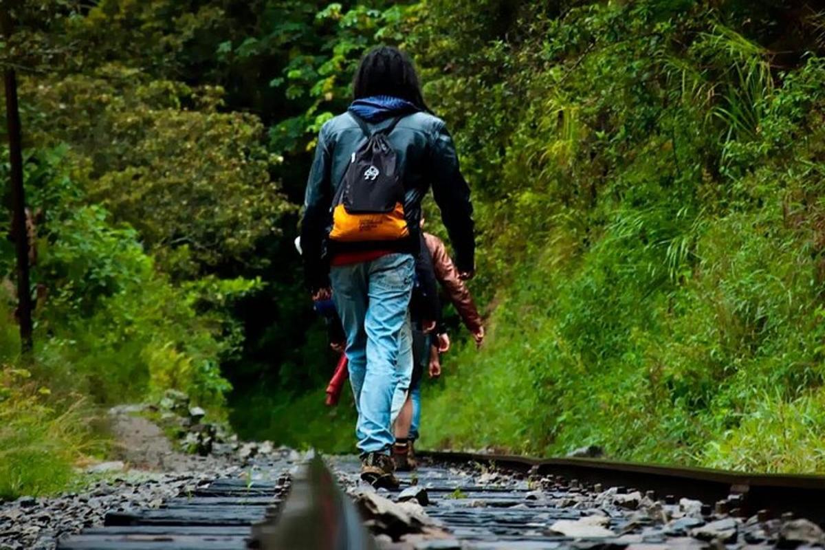 un uomo con uno zaino che cammina lungo i binari del treno