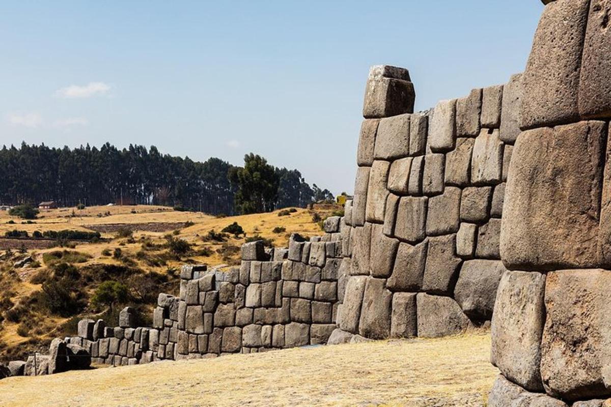un muro di pietra in un campo vicino a una collina