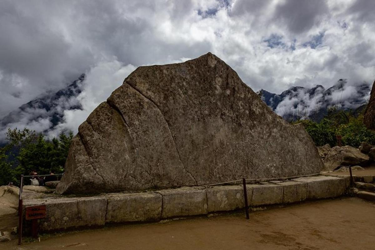 una grande roccia posta su una sporgenza di fronte a una montagna