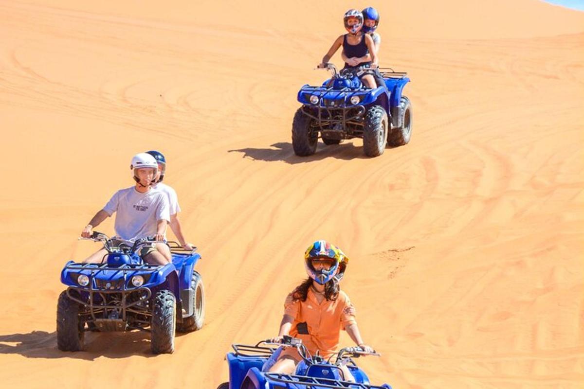 three people riding on atvs in the desert