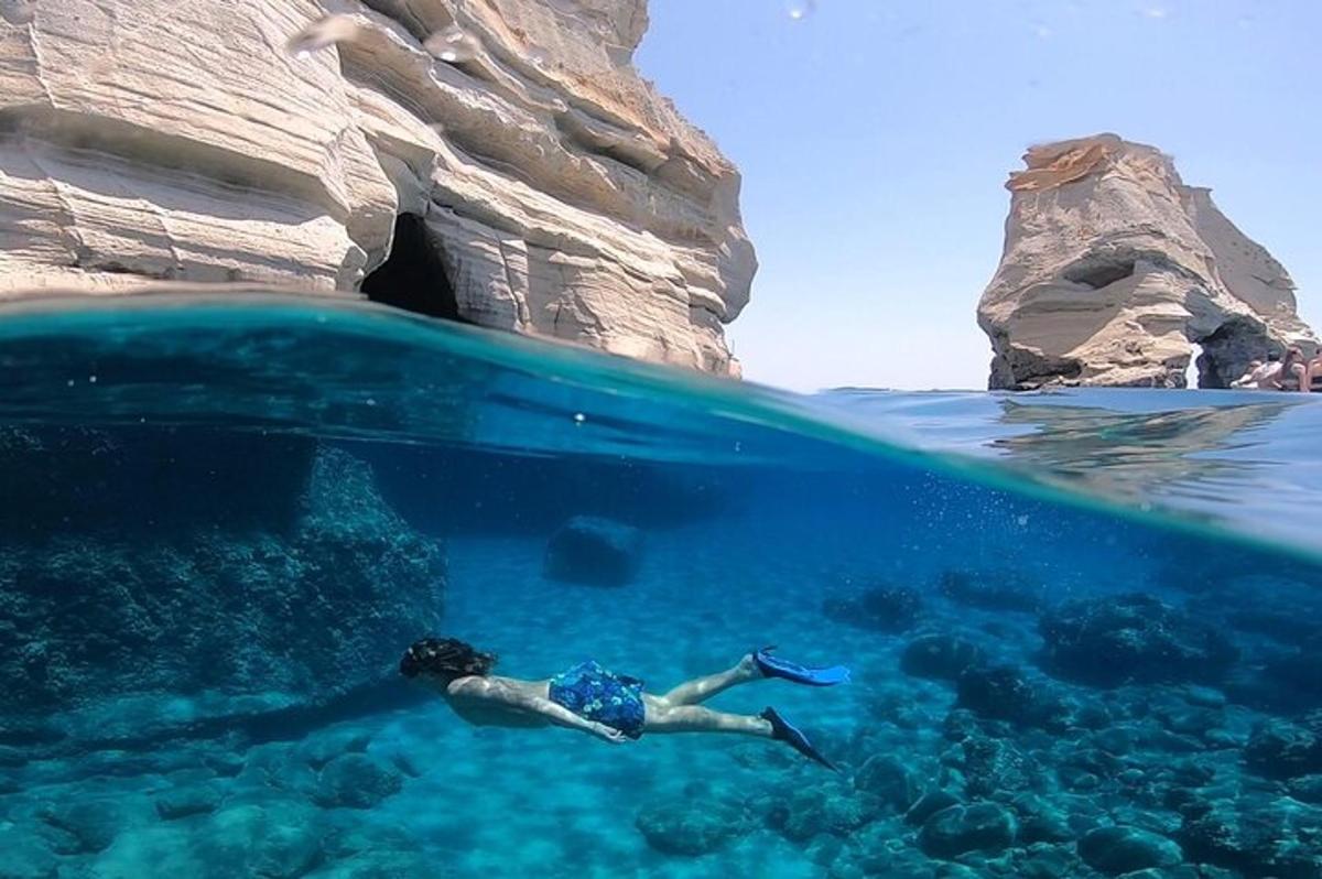a person swimming in the water near a rock formation