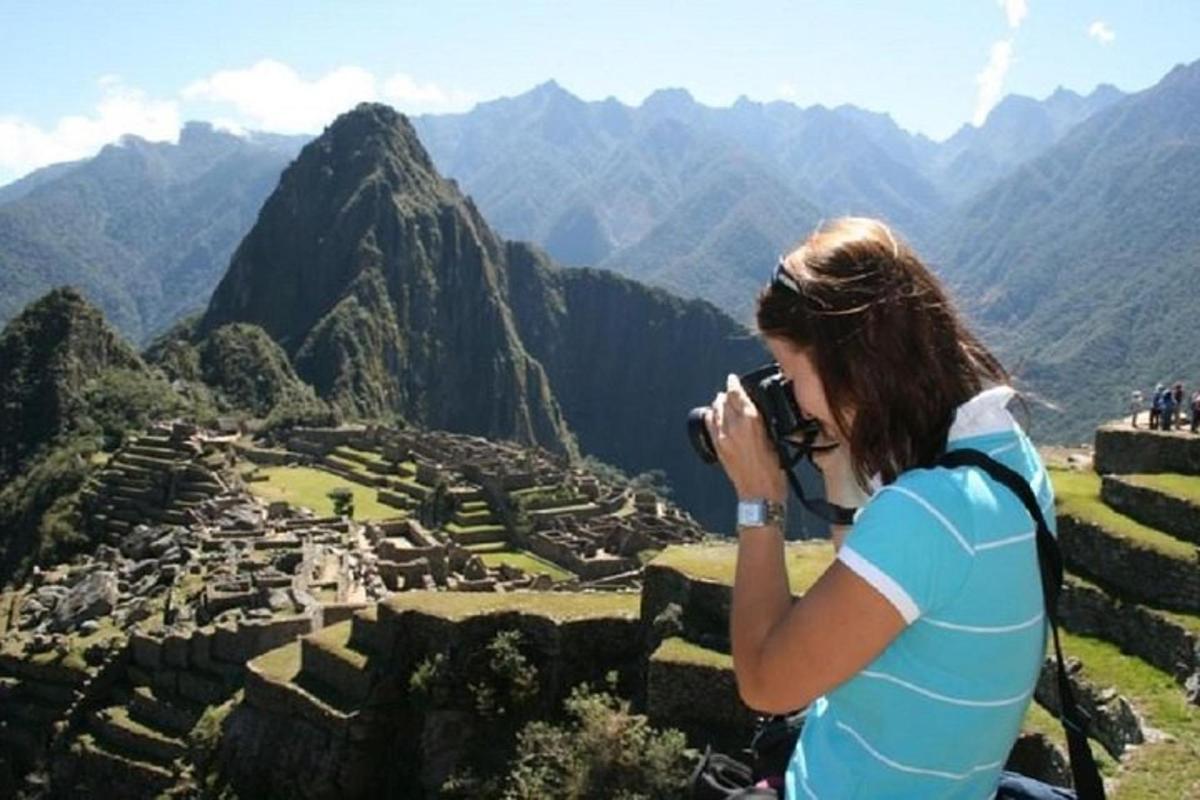 a woman taking a picture of a view of a mountain