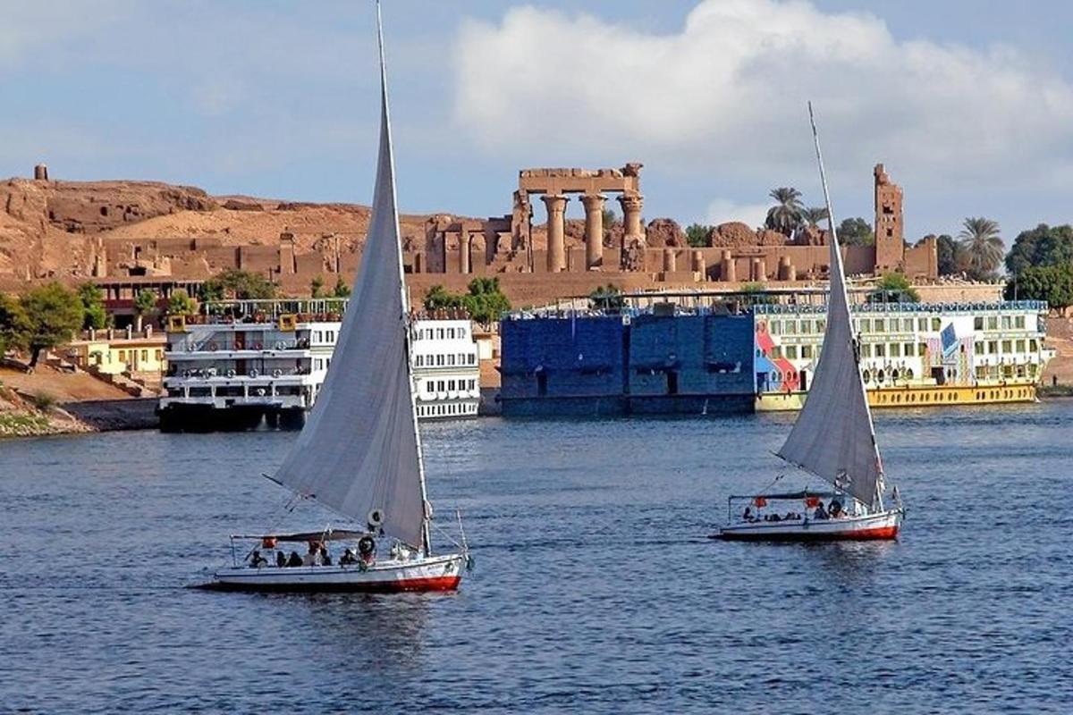 two small sailboats in the water in front of a city