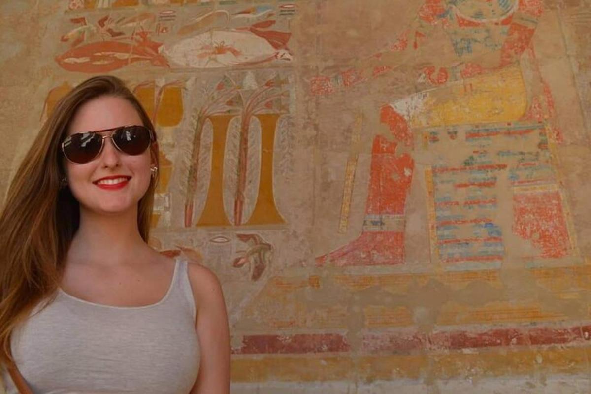 žena se slunečními brýlemi stojící před zdí