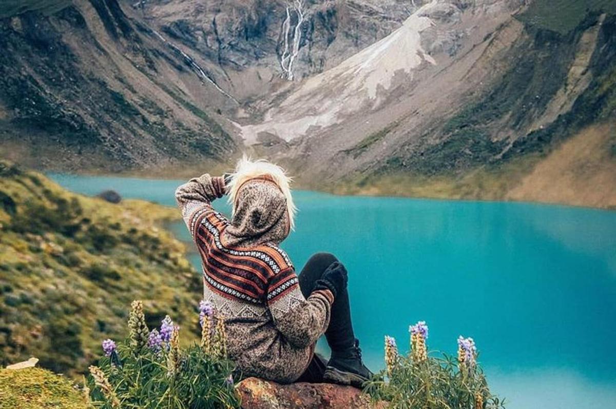 una persona seduta su una roccia che guarda un lago