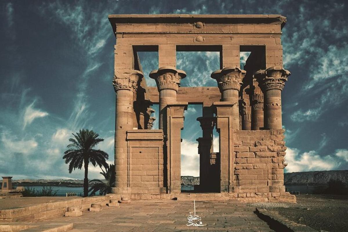 a stone building with columns and a palm tree
