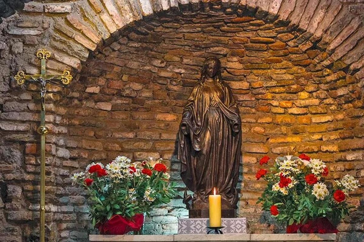 uma estátua em uma igreja com flores e uma vela