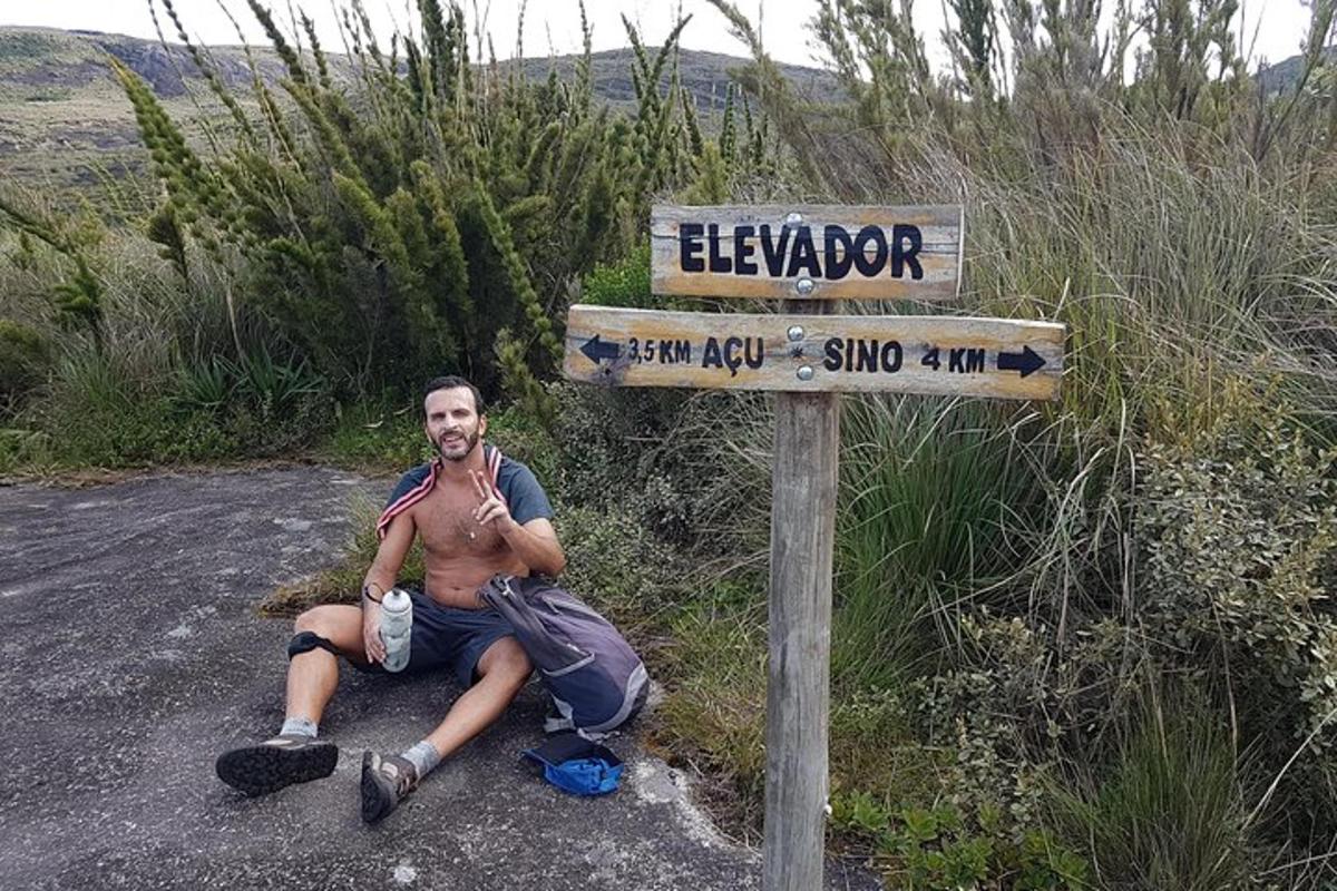 un uomo seduto sul ciglio della strada accanto a un cartello