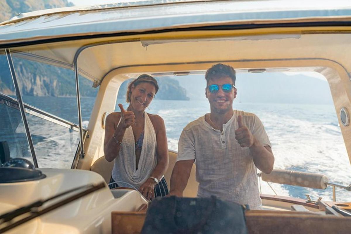 dois homens sentados em um barco fazendo sinal de positivo