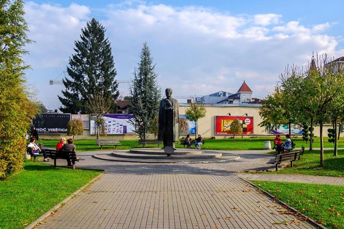 a statue in a park with people sitting on benches
