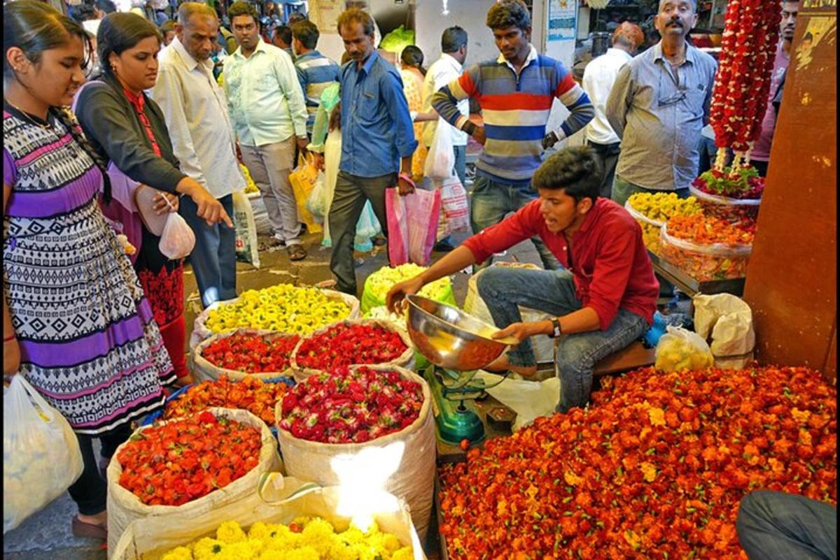 a group of people standing around a market with flowers