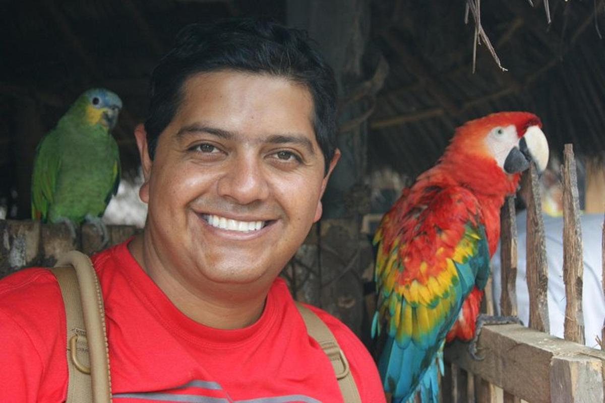 a man with two colorful birds on a fence