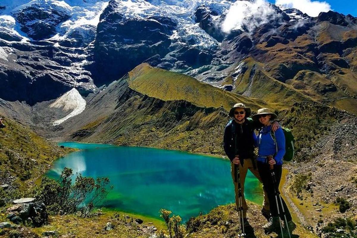 two people standing on top of a mountain with a lake
