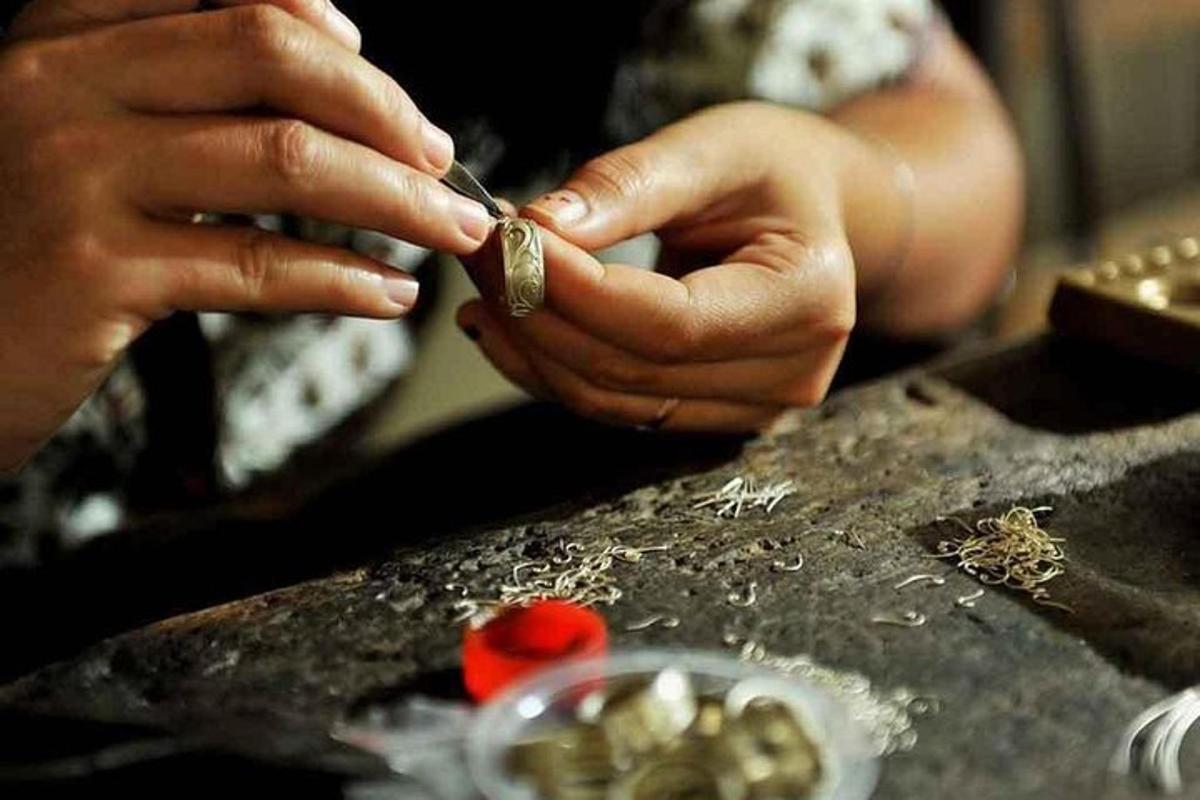 una persona che taglia un pezzo di metallo su un tavolo