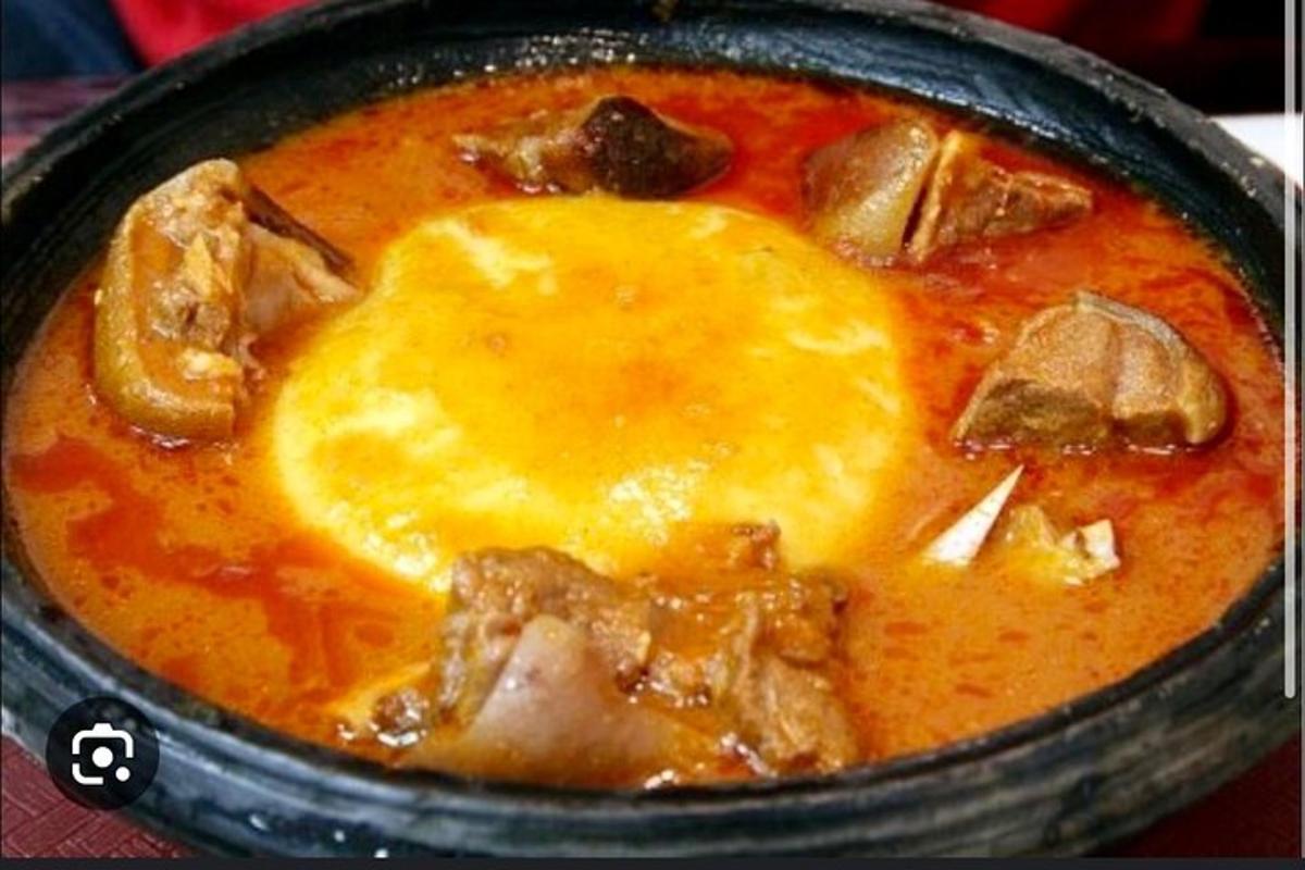 a black bowl of soup with meat and cheese