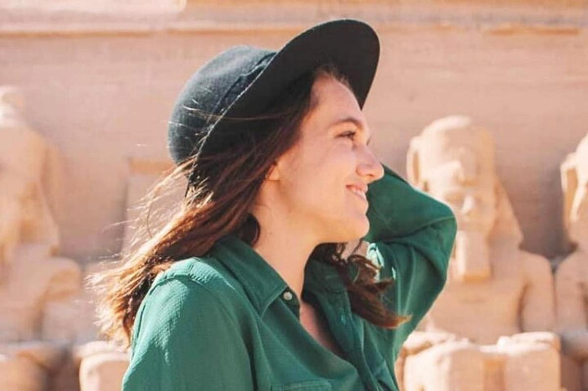 a woman wearing a hat standing in front of statues