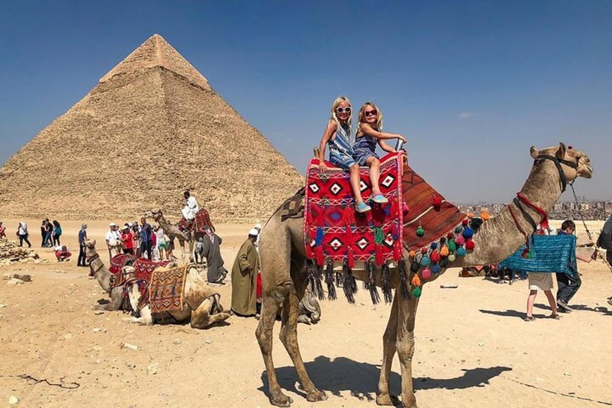 two people riding a camel in front of the pyramids