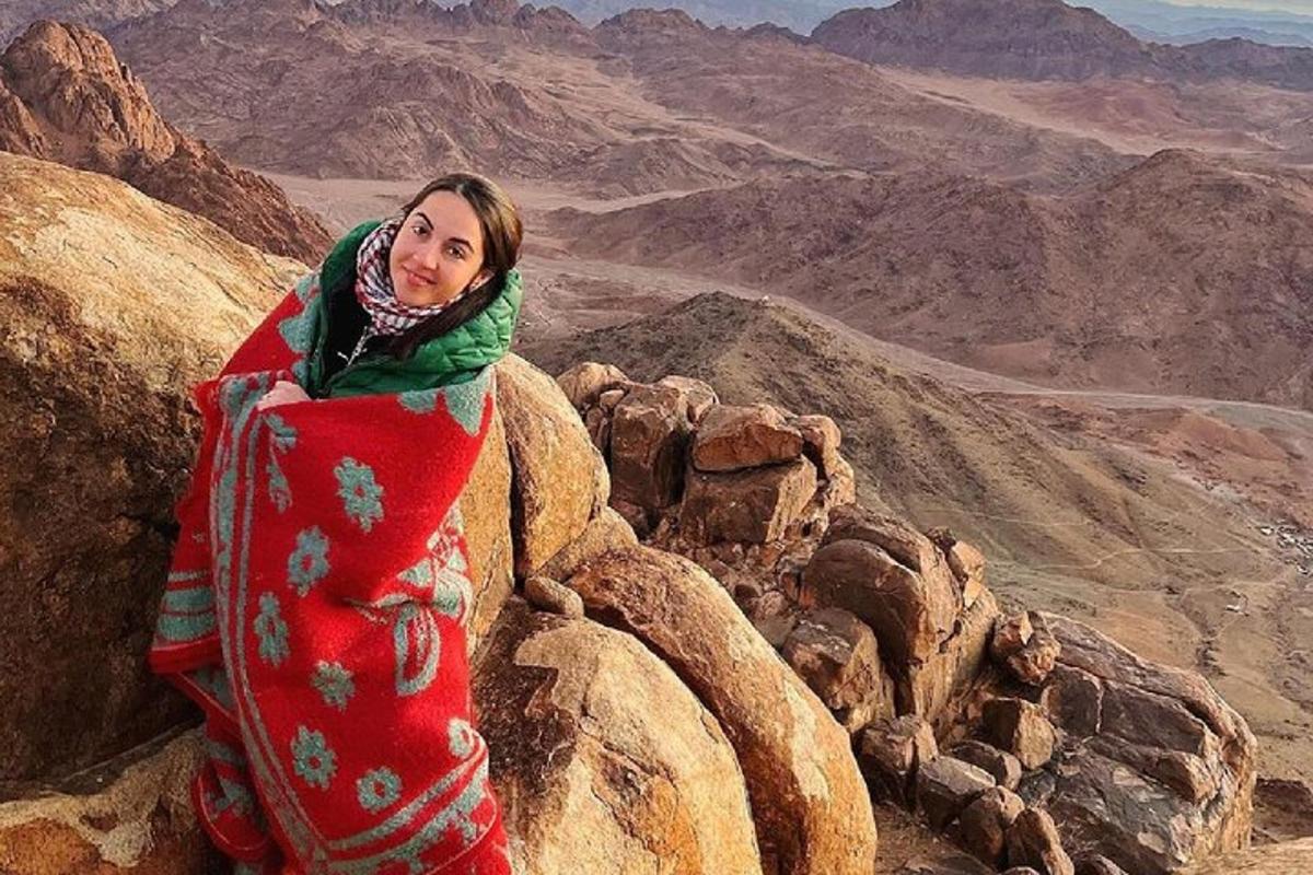 una mujer parada en la cima de una montaña