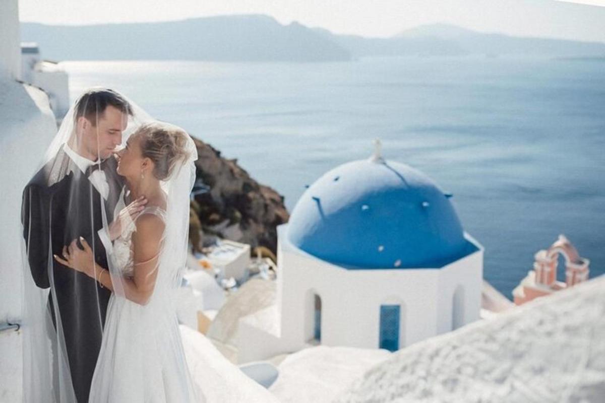 Una novia y un novio de pie junto a un edificio azul y blanco.