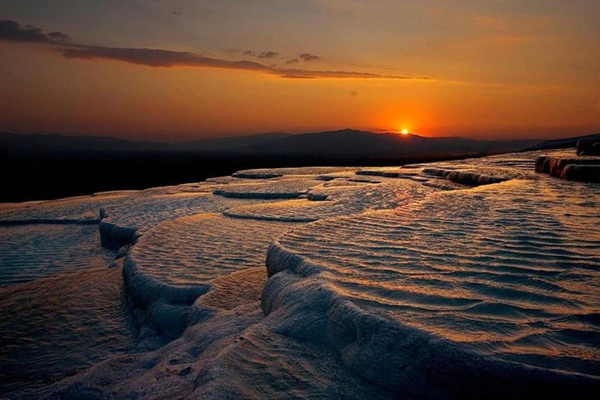 Una puesta de sol sobre un campo nevado con el sol al fondo