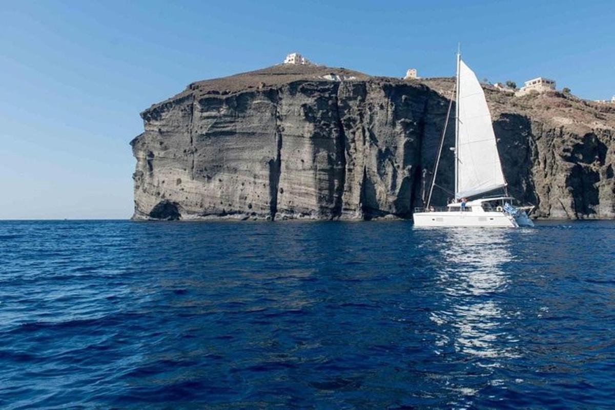 una barca a vela in acqua vicino a una grande roccia