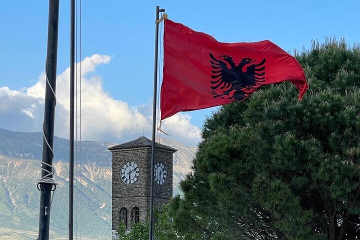 uma bandeira hasteada em frente a uma torre do relógio