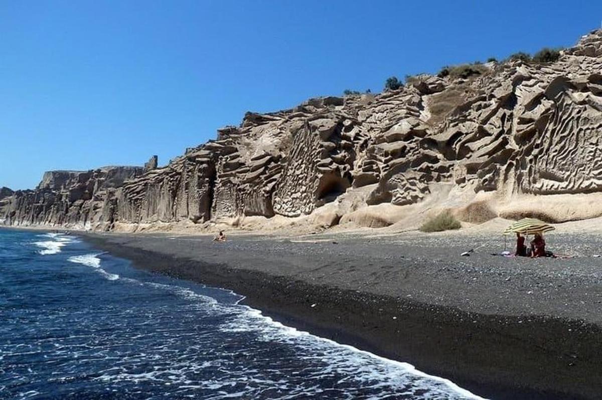 una playa de arena negra y un acantilado rocoso