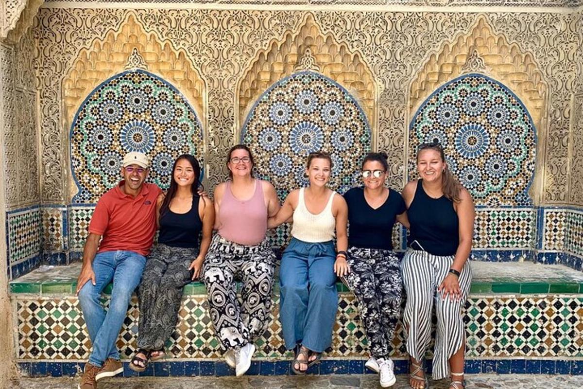 um grupo de pessoas sentadas em um banco em frente a uma parede