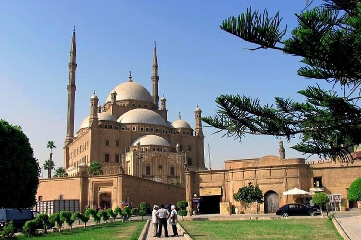 Un edificio con dos mezquitas con gente de pie delante.