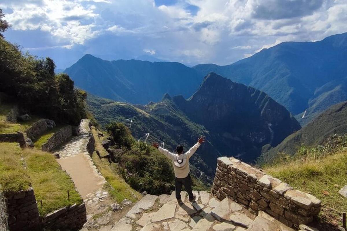 a man standing on a wall with his arms out on a mountain