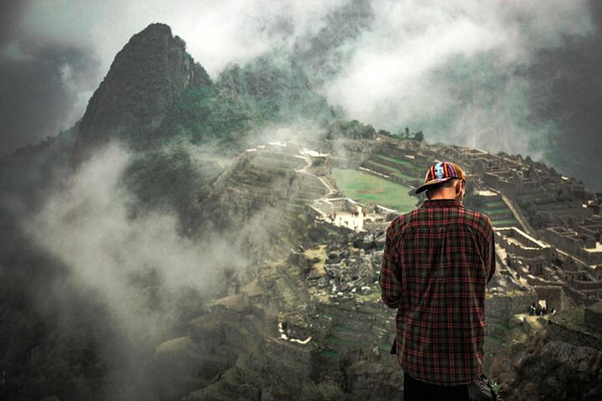 un uomo in piedi sulla cima di una montagna che domina una città