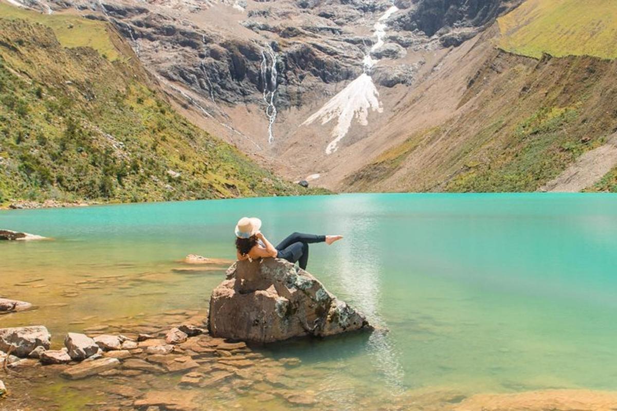una persona seduta su una roccia in un lago di montagna