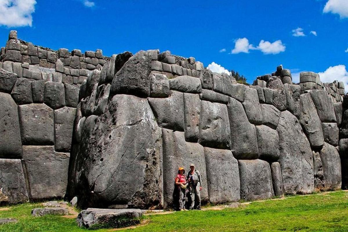 duas pessoas em pé em frente a um muro de pedra