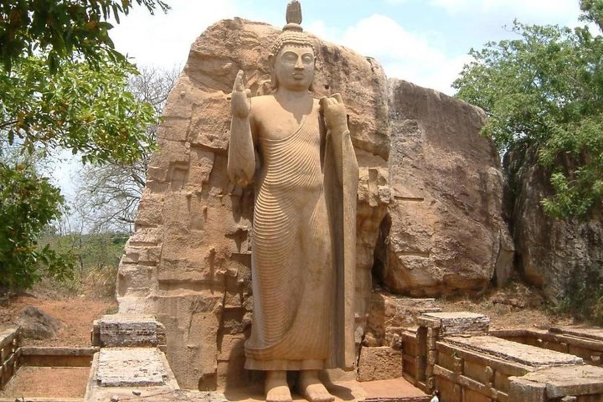 uma estátua de uma mulher em pé em frente a uma rocha