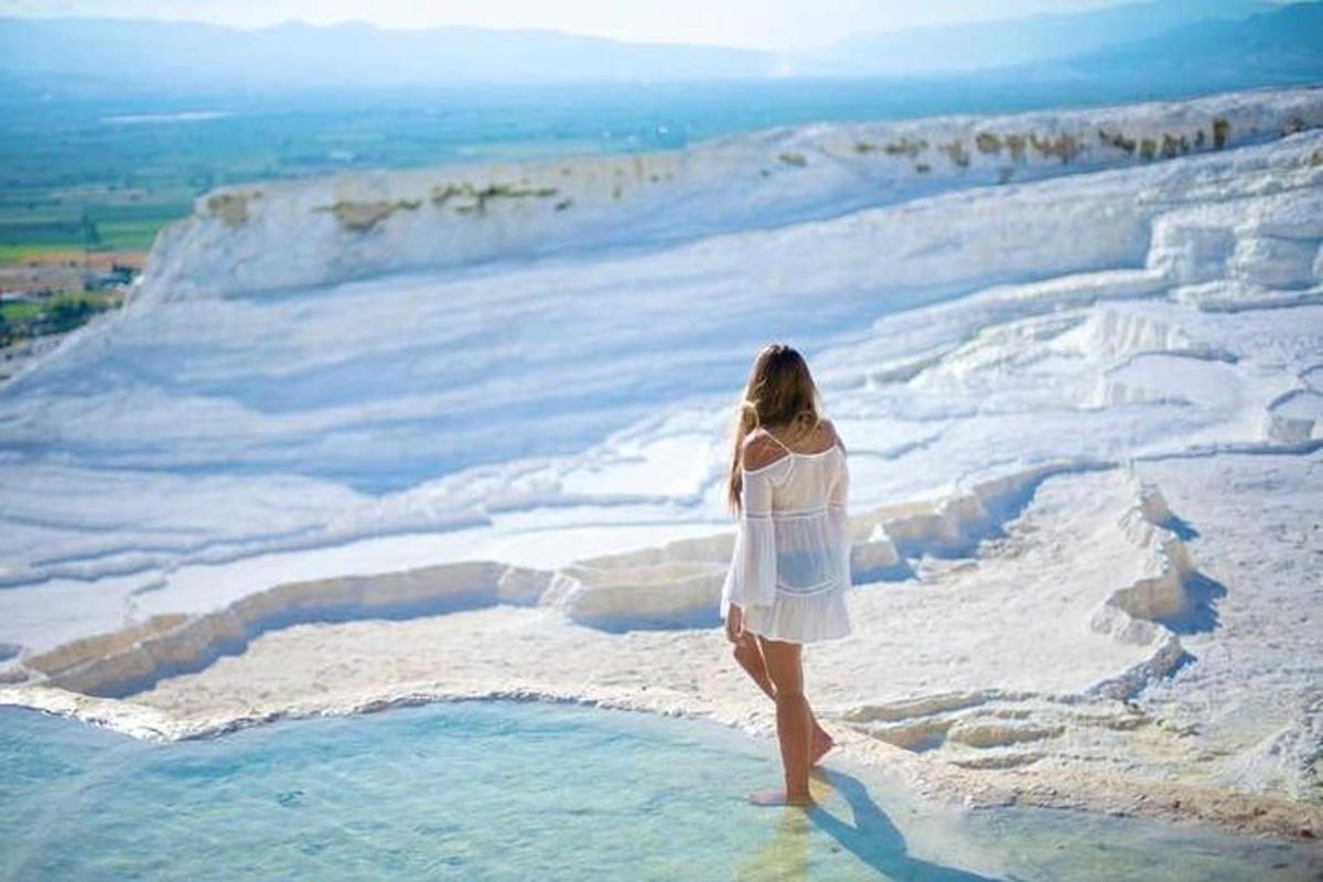 una donna in abito bianco in piedi in cima a una scogliera