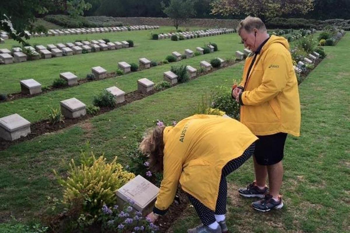 due persone in piedi in un cimitero che guardano i fiori