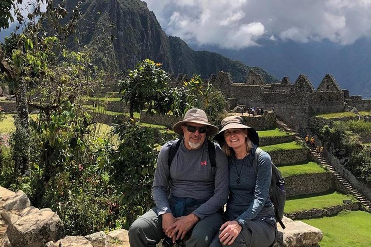 a man and a woman sitting on a wall with a mountain