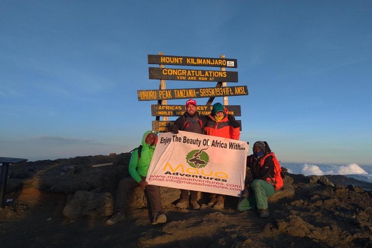 a group of people holding a sign on top of a mountain