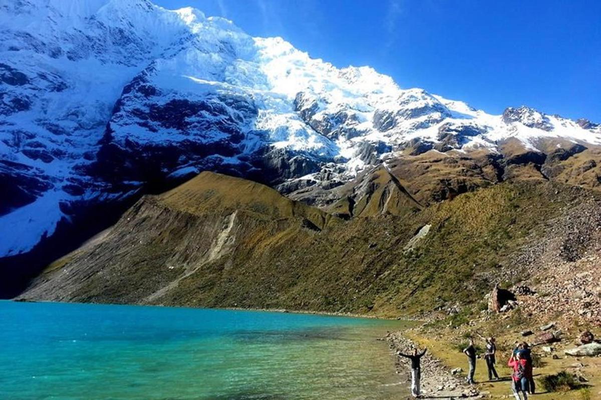 sekelompok orang yang berdiri di dekat gunung dengan danau