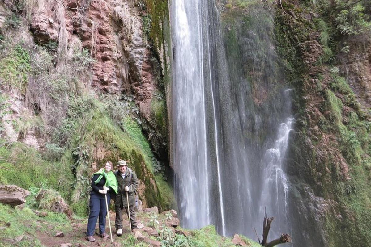 dua orang berdiri di depan air terjun