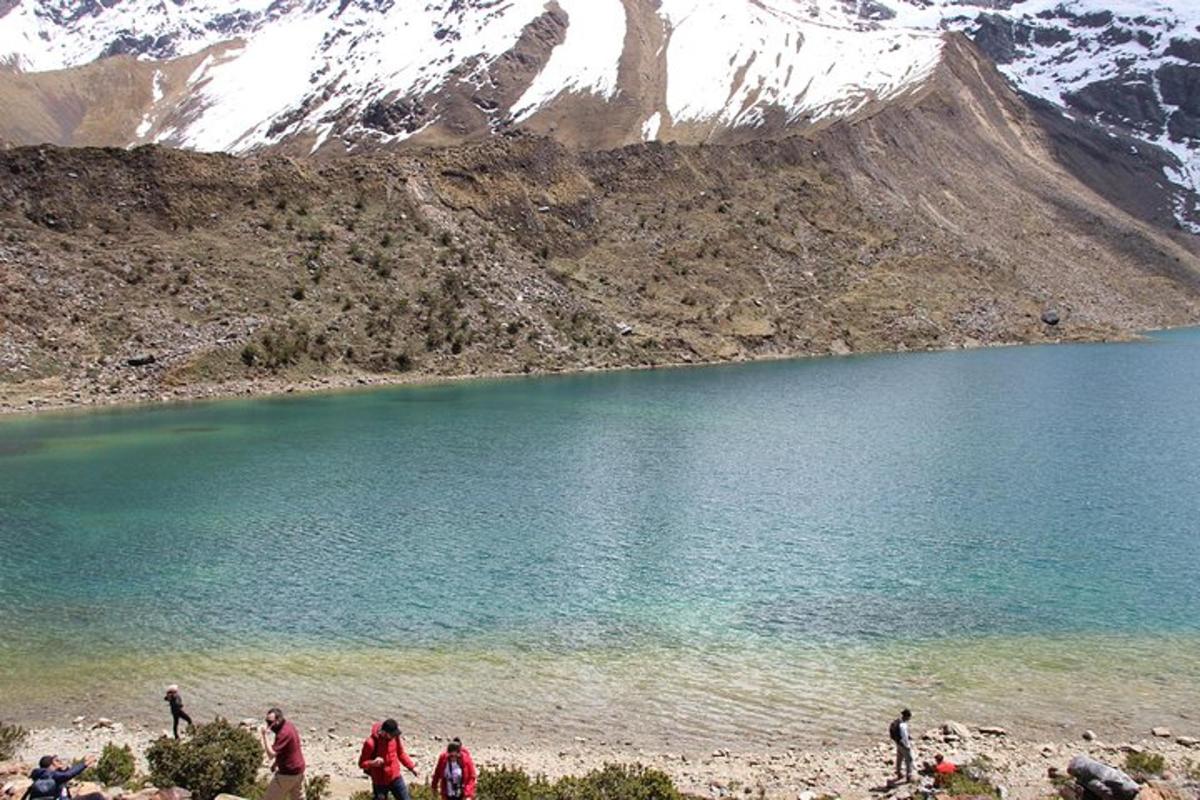 un gruppo di persone in piedi vicino a un lago di montagna