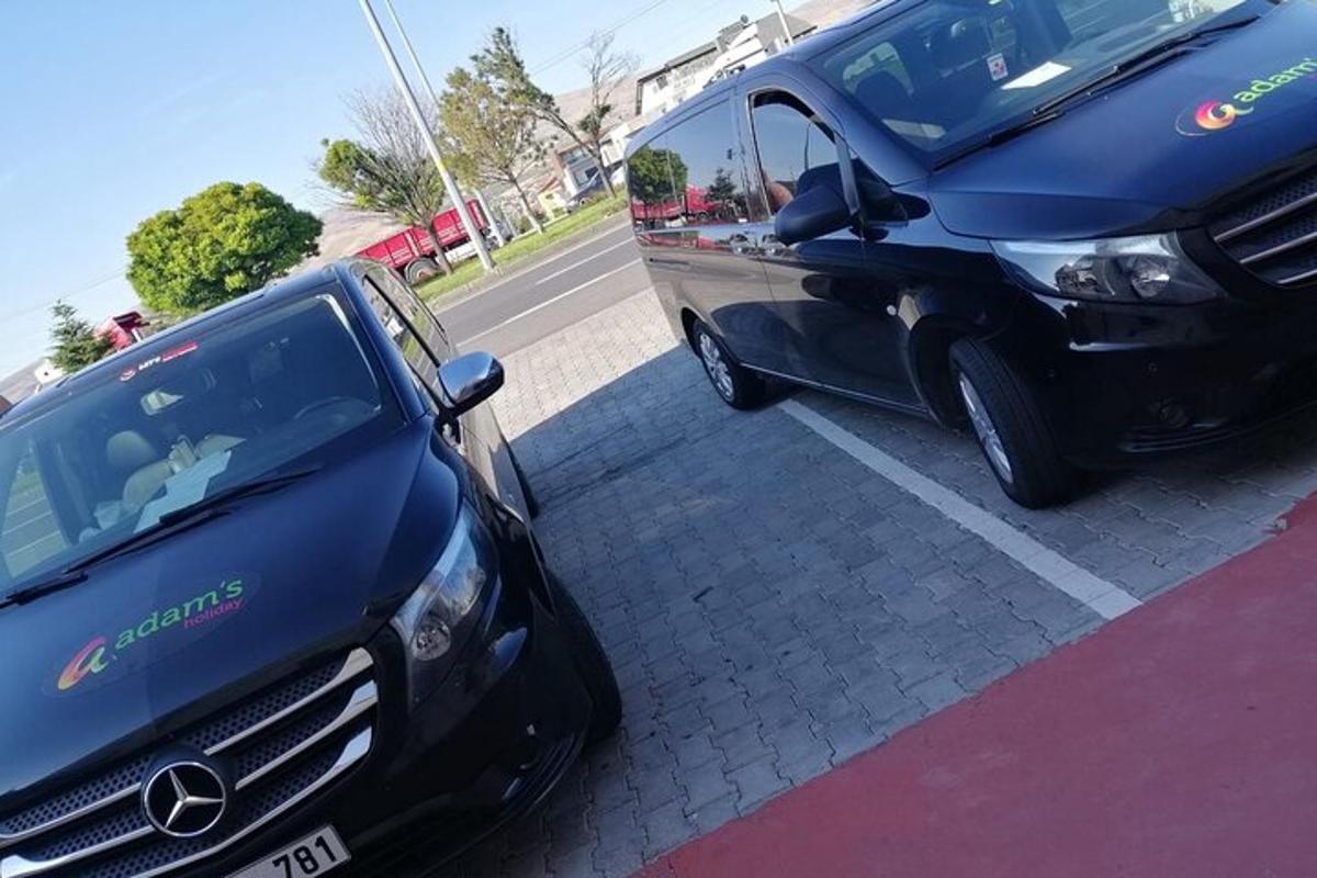 Una camioneta Mercedes estacionada al lado de un auto negro