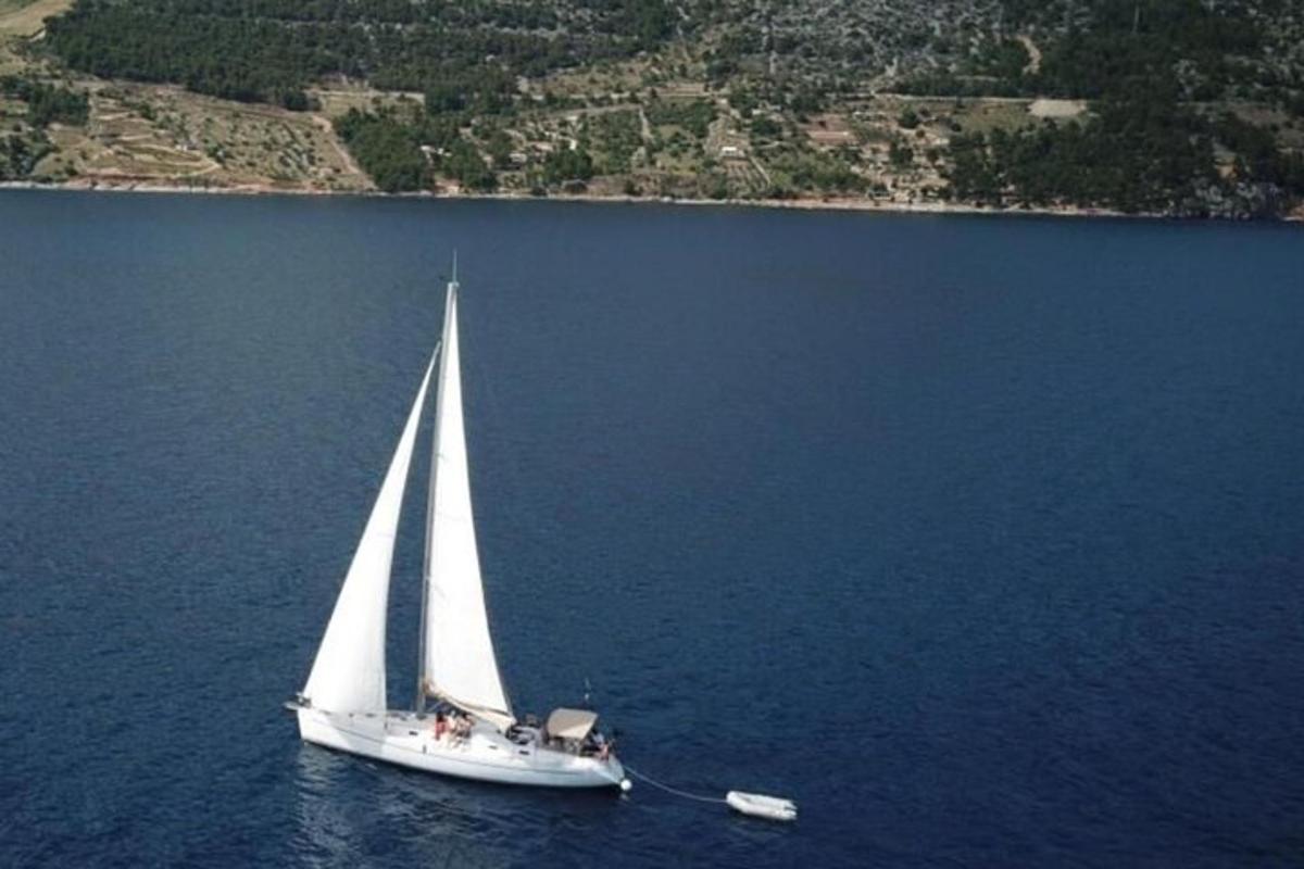 una barca a vela bianca in acqua con un'isola