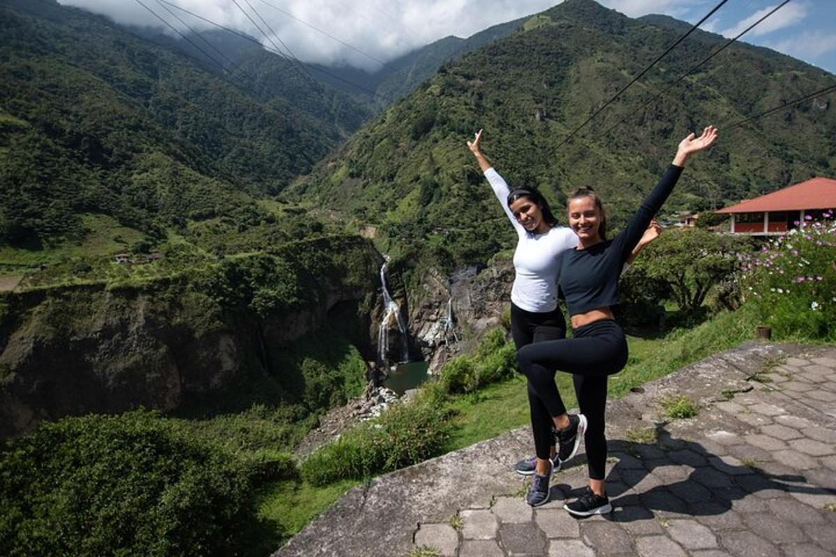 two women standing on top of a mountain with their arms in the air